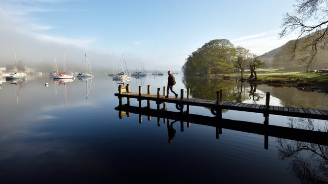 Woman walks out onto the jetty on a spring morning at Fell Foot